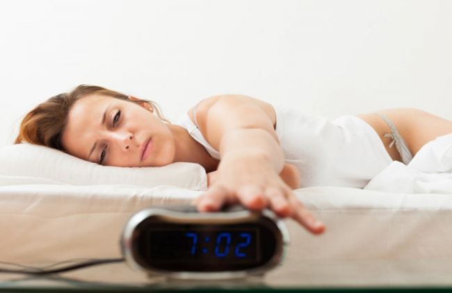 mujer-cansada-cama-despertador